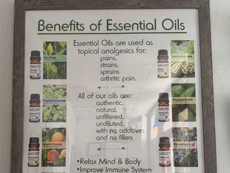 A framed poster lists the benefits of essential oils, showing images of oils and plants, and claims uses for pain relief, relaxation, and immune support.